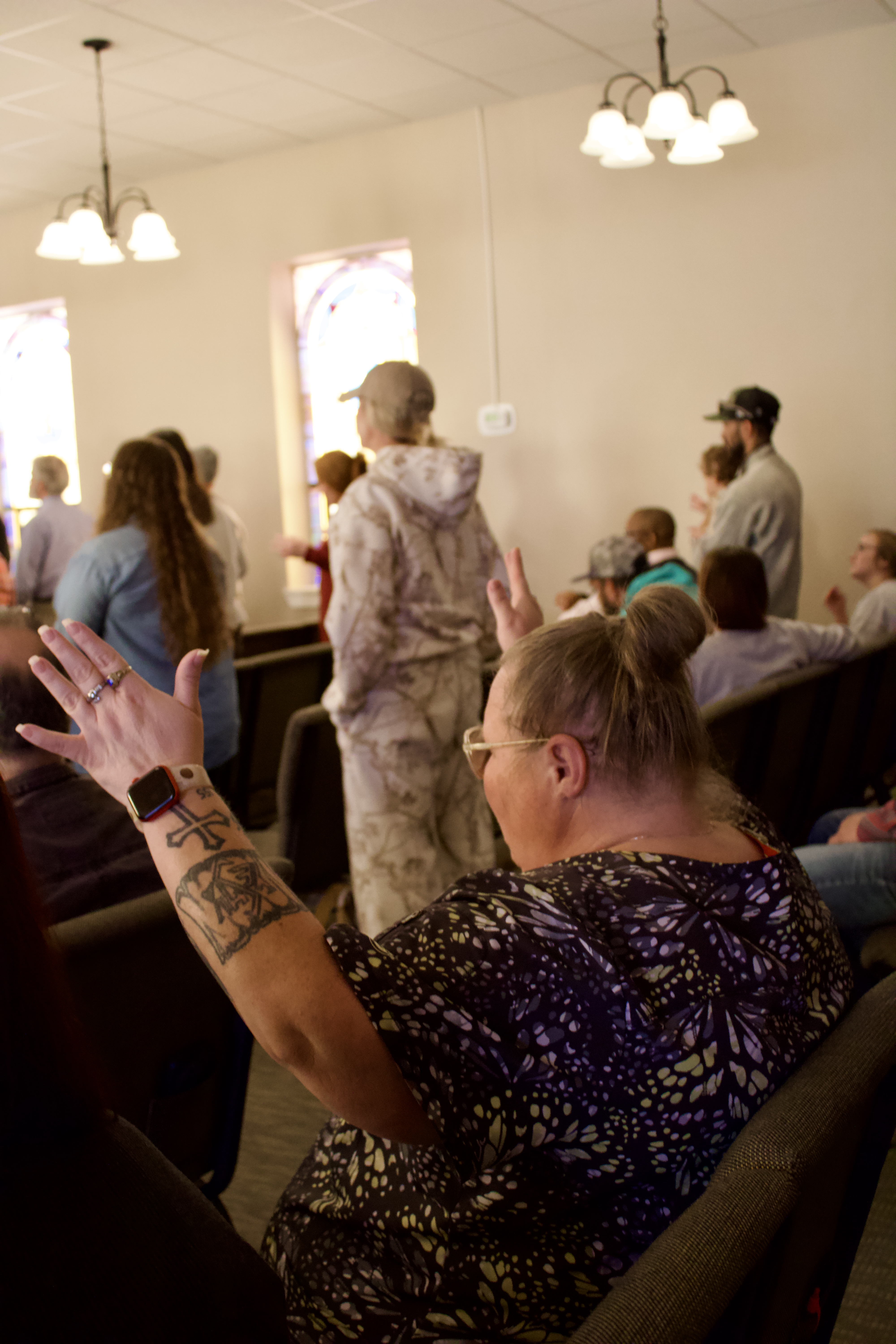 A full sanctuary at Relentless Worship Center during worship, with a woman lifting her hand in praise