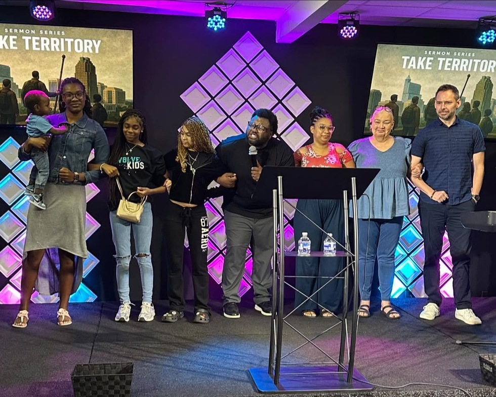 A multigenerational group holding hands on the church stage
