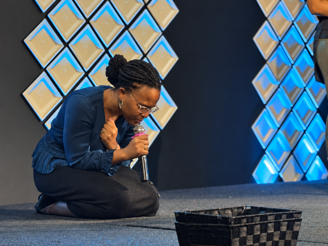 A woman kneeling in prayer at Life Changers Church NC