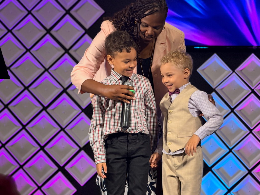 Two children participating with a microphone alongside an adult at church